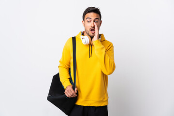 Young sport man with sport bag isolated on white background whispering something with surprise gesture while looking to the side