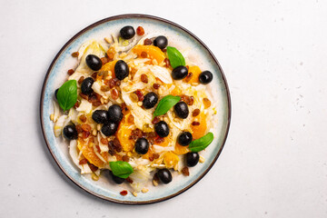 Fennel, orange and olives salad, with raisins, pine nuts and basil leaves.