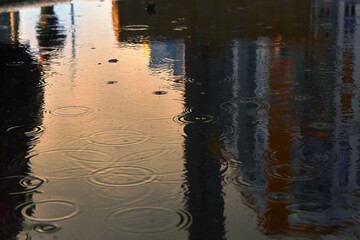 Fototapeta na wymiar Drops of rain bubbling in a puddle with the reflection of light