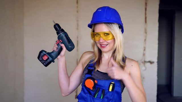 Young attractive female builder or worker showing thumbs up