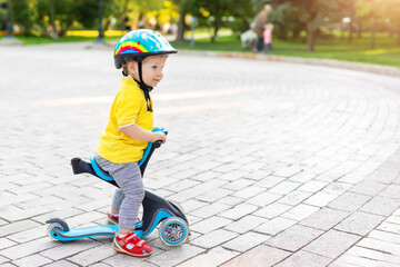 Cute adorable little caucasian toddler boy portrait in helmet having fun riding three-wheeled...