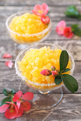 Orange granita, frozen summer dessert in two glasses, blooming japanese quince dressing