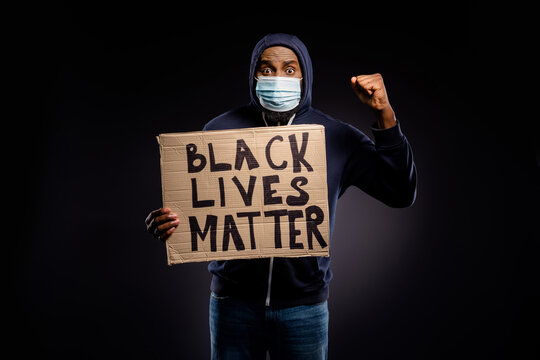 Photo of amazed afro american guy hold cardboard banner black lives banner raise fists celebrate discrimination stop victory hope inspire wear medical mask jumper sweater isolated background