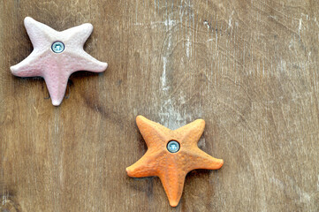 Orange and pink starfish toys on wooden background with copy space