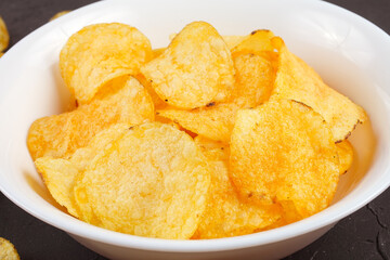 potato chips in a white bowl on a dark background