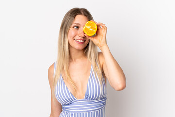 Young blonde woman isolated on white background in swimsuit and holding an orange