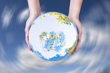 Earth globe puzzle reconstruction concept with planet model hold in hands