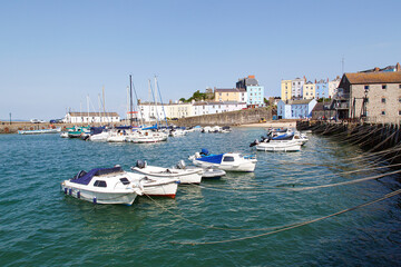 Fototapeta na wymiar Boats moored in Tenby Harbour at high tide. The harbour is built into a corner of North Beach between the old medieval walled town and castle hill.