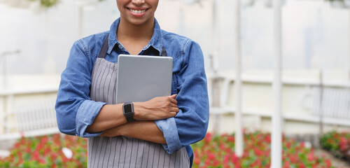 Smart greenhouse concept. African american smiling girl presses tablet to chest