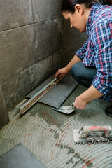 Female bricklayer checking the floor with a level to install a tile floor