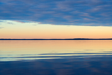 Fototapeta premium Water surface. View of a Sunset sky background. Dramatic gold sunset sky with evening sky clouds over the sea. View of a Crystal clear sea water texture. Landscape. Small waves. Water reflection