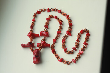 Red beads made of natural coral and copper wire on a white background.