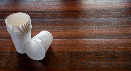 Vasos de plástico blanco desechables sobre una mesa de madera oscura