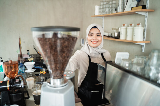 female waitress holding a coffee grinder preparing to make coffee