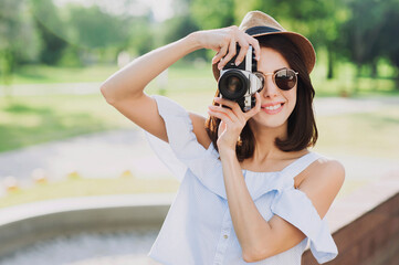 Young woman photographer takes photographs with camera in a city. Travel, vacations, hobby, leisure, work and active lifestyle concept