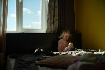 Portrait of a playing girl at home in the sun on a yellow wall