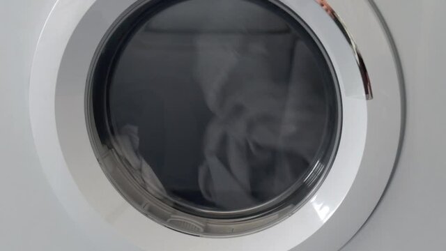 housework routine concept. clothes spinning inside a dryer laundry machine.