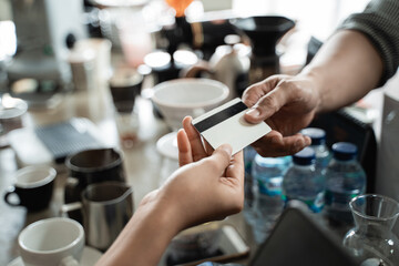 close up hand of the buyer gives a credit card to the seller to pay at the cafe