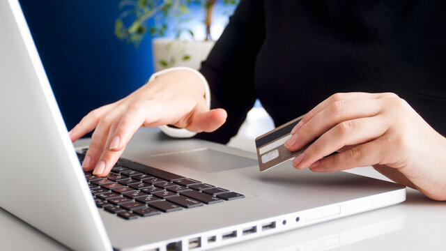 Closeup image of young woman shpping online holding plastic credit card
