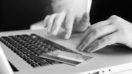 Fototapeta na wymiar Black and white image of credit card lying on laptop keyboard. Concept of online shopping and e-commerce