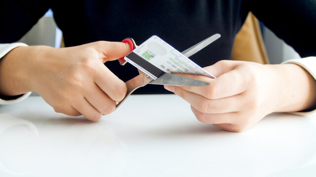 Closeup image of female bank worker cutting plastic credit card