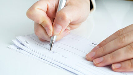Closeup image of person signing banking cheque