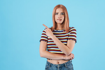 Image of nervous girl in striped t-shirt pointing fingers aside