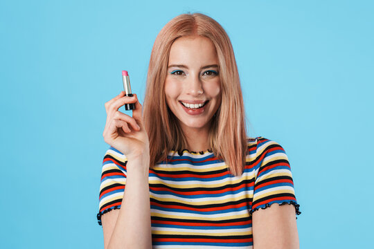 Image of happy caucasian girl smiling at camera and holding lipstick