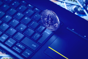 Dollar bills, black keyword and metal souvenir bitcoin. The concept of electronic money, online...