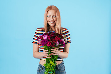 Image of cheerful beautiful pretty girl posing with flowers and smiling