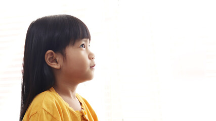 Cute little Asian baby girl looking up thinking something isolated on white background, side profile. Hope concept