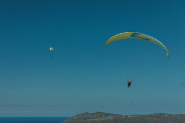 Two paragliders are flying in the sky