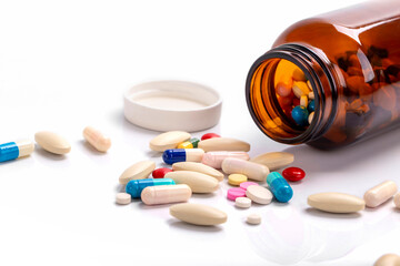 Closeup on pills capsules spilling out of pill bottle isolated on a background , Healthcare and medical drugs concept