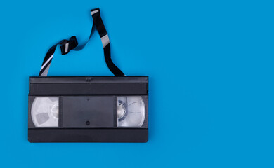 Broken VHS tape from the 80s and 90s on blue background and space to write on it