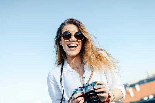 Happy young tourist smiling with sunglasses and camera