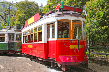 Fototapeta na wymiar Historic red tram against trees, part of the tramway network since 1873, Lisbon, capital city of Portugal.