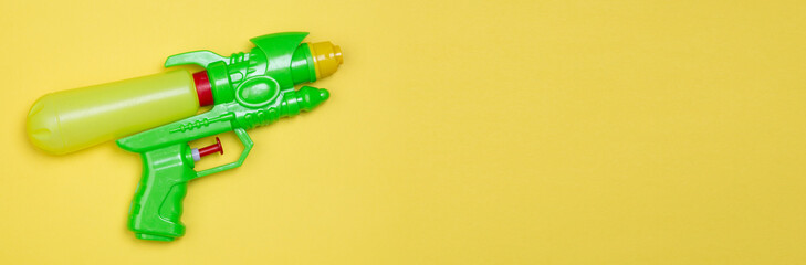 green toy water gun on yellow background