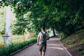 Sofia Park, Uman. A man with a backpack walks along the lake embankment. Male tourist with a colored backpack in the park with a fountain.
