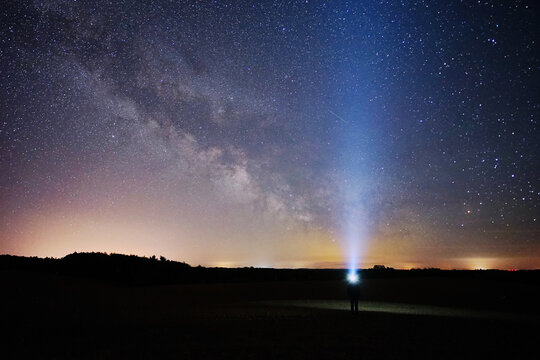 Stargazing person with headlamp with the milyway and the universe in Germany 