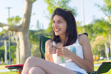Portrait of smiling woman sitting on bench in park