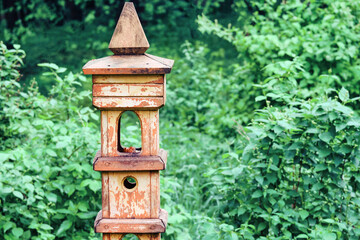 Fototapeta na wymiar Retro pillar with bird feeder and squirrels in the park.