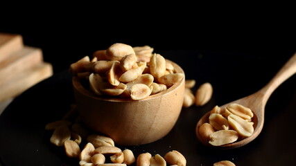 Roasted peanuts are placed on a dark floor.