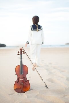 Violin on the beach with a child walking away on the blurry background - musical concept