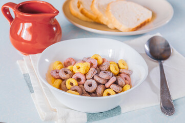 multi-colored cereal rings in a white plate and red milkman