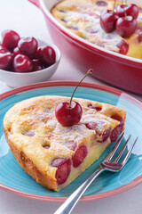 A piece of clafoutis with cherry on a plate