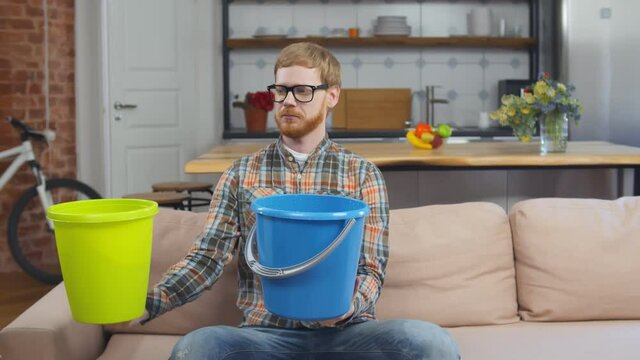 Man Using Buckets For Collecting Water Leakage From Ceiling