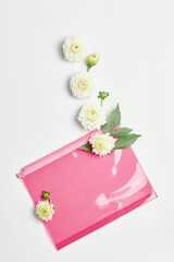 pink transparent cosmetic bag and white fresh flowers. simple flat layout, top view