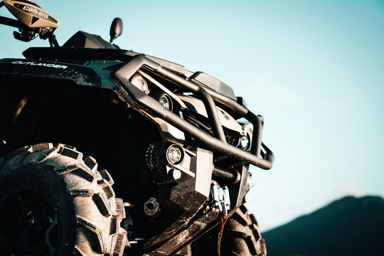 Detail close up of army green can-am outlander atv quad motorcycle bike's front light. It look's like very aggressive and strong off - road vehicle.