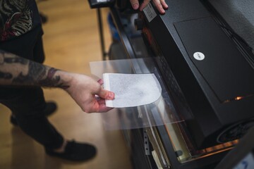 High angle shot of a tattoo artist working with a lamination machine