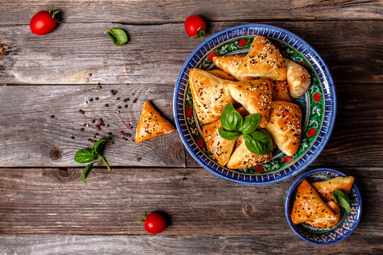 Uzbek national dish samosa. Indian samosas baked pastry with savoury filling, popular Indian snacks, served in bowl with spices on rustic background, top view